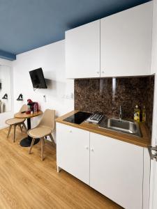 a kitchen with white cabinets and a sink and a table at Mini Studio N6 private Bathroom and Kitchenette in Limassol