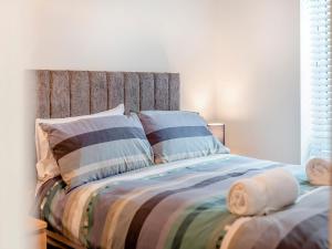 a bed with a striped comforter and pillows at Martin - Uk48161 in Filey +7 photos