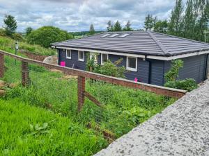 a blue house with a fence in front of it at Craigpark Lodge in Caldercruix