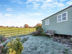 a bench sitting outside of a house with a field at Shepherds Hut - Uk45529 in Buildwas