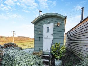 a small green house with a door on the side of a house at Shepherds Hut - Uk45529 in Buildwas
