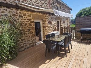 a patio with a table and chairs on a wooden deck at Gîte l'étable détente SALLE SPA EN SUPPLEMENT in Vautorte