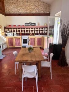 a kitchen with a wooden table and white chairs at Gîte Landes d armagnac in Roquefort