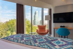 a hotel room with a bed and a chair and a window at Sadu Hotel Almaty, a member of Radisson Individuals in Almaty