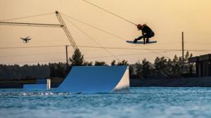 a man on a snowboard jumping over a ramp in the water at Pirtelių resort - Pilkasis namelis in Kiauleikiai