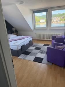 a bedroom with a bed and a couch and two windows at Rheinblick Appartements in Remagen