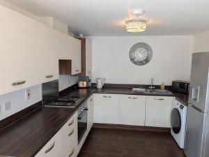 a kitchen with white cabinets and a clock on the wall at Rothwell in Swansea