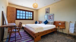 a bedroom with a bed and a desk and a window at Bio et Bois -Luxury Bio Farm- in Moulay Yacoub