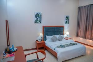 a hotel room with a bed and a table and a desk at Rostel Villa Hotel in Mbeya
