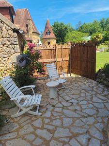 two chairs and a table on a stone patio at Chambre de la Tour 2 in Milhac