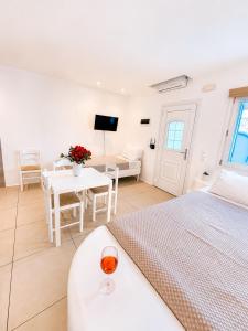 a white room with a bed and a table with a wine glass at Crystal Suites in Mikonos