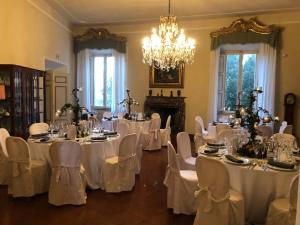 a room with white tables and chairs and a chandelier at castello di sovicille in Sovicille +84 photos
