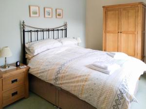 a bedroom with a large bed with a wooden dresser at Cropple Howe in Threlkeld +5 photos
