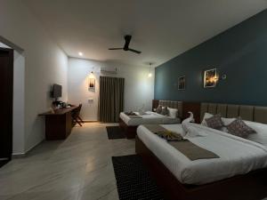 a hotel room with two beds and a desk at The Fox Resort, Bandipur in Bandipūr