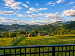 a field with a fence and mountains in the background at Gacka Luxury Mountain Villa in Feratovo Polje
