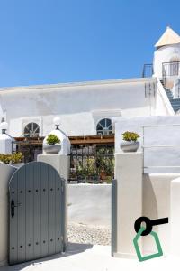 a door in front of a white building with plants at Hotiday Santorini Mesaria in Fira