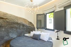 a bedroom with a bed and a large rock at Hotiday Santorini Mesaria in Fira