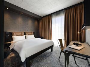 a bedroom with a large white bed and a desk at ibis Styles Friedrichshafen in Friedrichshafen +78 photos