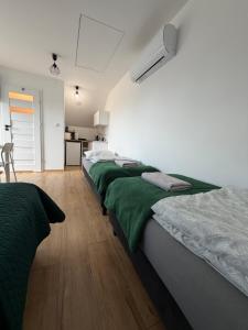 a bedroom with three beds with green sheets at Przystanek Zator in Zator