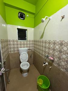 a green bathroom with a toilet and a shower at Hotel Diyo inn in Guwahati