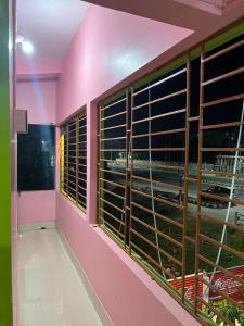 a room with pink walls and large windows with blinds at Hotel Diyo inn in Guwahati