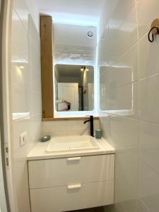 a white bathroom with a sink and a mirror at Appartement proche Château de Compiègne in Compiègne