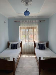 two beds in a room with a window at Guest House Dimos Kristi in Përmet