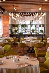 a restaurant with white tables and yellow chairs at Sadu Hotel Almaty, a member of Radisson Individuals in Almaty