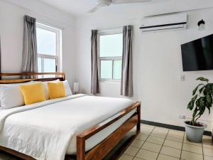 a bedroom with a bed with yellow pillows and a tv at Alma Vida Hotel in Manuel Antonio