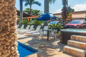 a patio with a table and chairs next to a pool at Pousada Acqua Bella PISCINA CLIMATIZADA in Bertioga