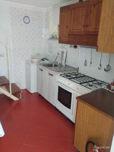 a kitchen with a white stove and a red floor at Casa vacanze Torre in Cefalù
