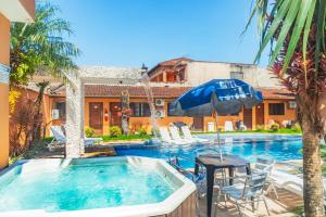 a swimming pool with a table and an umbrella at Pousada Acqua Bella PISCINA CLIMATIZADA in Bertioga