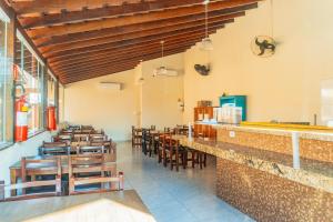 a restaurant with wooden chairs and a bar at Pousada Acqua Bella PISCINA CLIMATIZADA in Bertioga