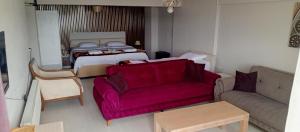 a living room with a red couch and a bed at Ayışık Otel in Hamidiye