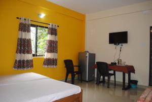 a room with a bed and a desk and a television at Joe And Marietta's Guesthouse in Calangute