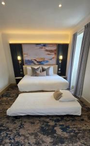 two beds in a hotel room with white sheets at Trouville Bournemouth - OCEANA COLLECTION in Bournemouth