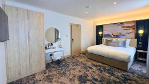 a hotel room with a bed and a mirror at Trouville Bournemouth - OCEANA COLLECTION in Bournemouth
