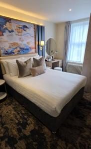 a bedroom with a large bed with a large white bedspread at Trouville Bournemouth - OCEANA COLLECTION in Bournemouth