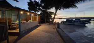 a boat is parked next to a house on the water at NATA homestay in Banggai