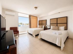 a bedroom with two beds and a flat screen tv at Zona Dorada Living in Mazatlán