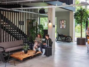 a man and woman sitting in a lobby with a table at Hotel Valkenburg by Mercure - Next to Shimano Experience Center in Valkenburg