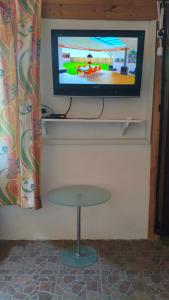 a television on a wall with a table in front of it at Kamilla Vendégház in Ács