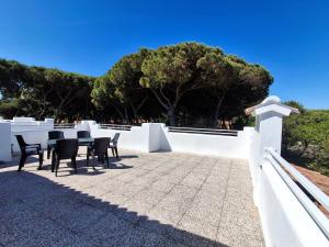 a patio with chairs and a table and a white wall at Attico Resplendor Fronte mare in Rosolina Mare