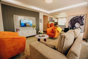 a living room with orange furniture and a horse painting on the wall at Rouse precious haven in Nakuru