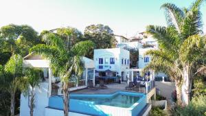 a large white house with a swimming pool and palm trees at Ilhas Gregas Chalets in Lavras Novas