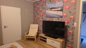 a living room with a flat screen tv and a chair at Ferienwohnung Müller in Bestwig