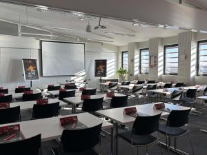 a classroom with tables and chairs and a projection screen at ibis Lyon Sud Oullins in Oullins