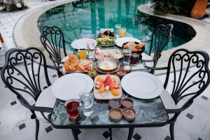 a dining table with food and drinks and a pool at Elegance East Hotel in Antalya
