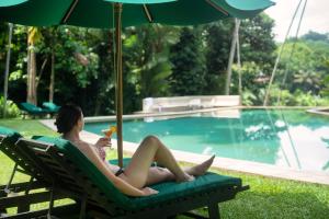 a man laying in a chair with an umbrella next to a swimming pool at Adigars Manor Kandy - A Boutique Heritage Hotel Built in 1804 in Kandy