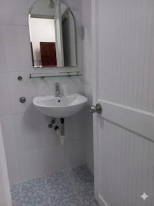 a white bathroom with a sink and a mirror at Nhà nghỉ KIM VÀNG in Phú Quốc
